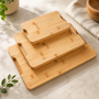 Set of Nolly Home bamboo cutting boards on a marble surface with a plant and towel in the background.